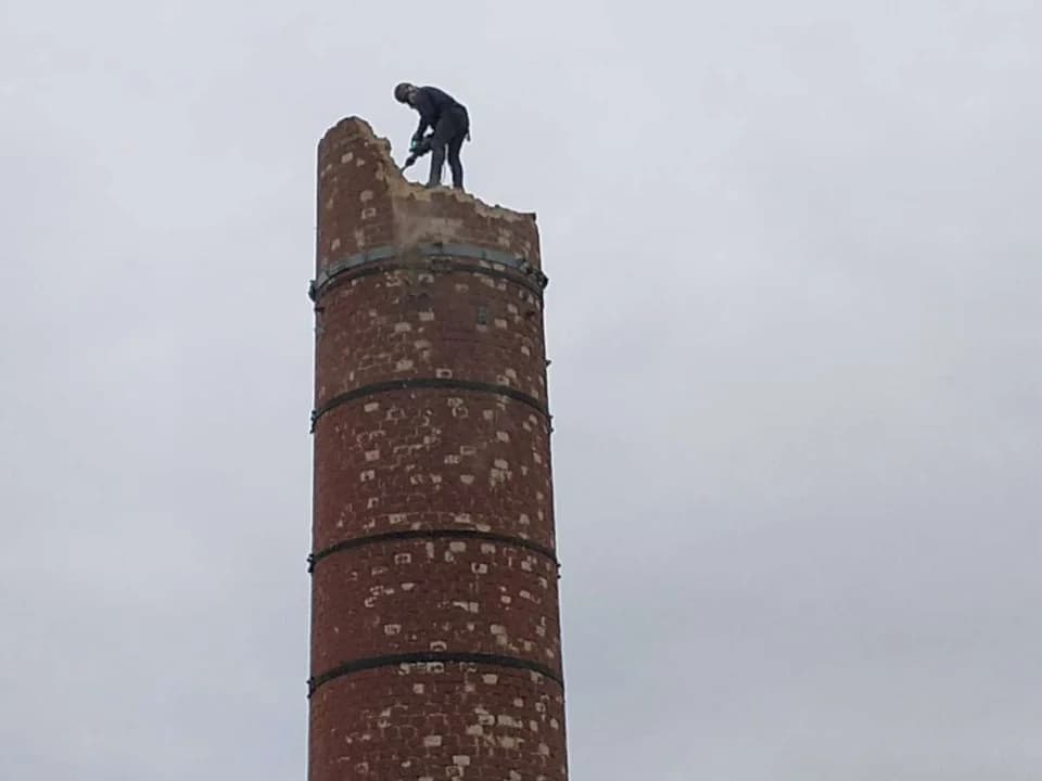 Ze względu na to, że komin był za wysoka do wyburzenia w całości, pracownik wrocławskiej firmy - uzbrojony w specjalny młot i zabezpieczony uprzężą - przez kilka dni skracał komin z 22 metrów do 15.