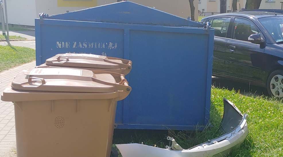 Zderzak od samochodu obok kontenera. Gdzie wyrzucać części samochodowe?